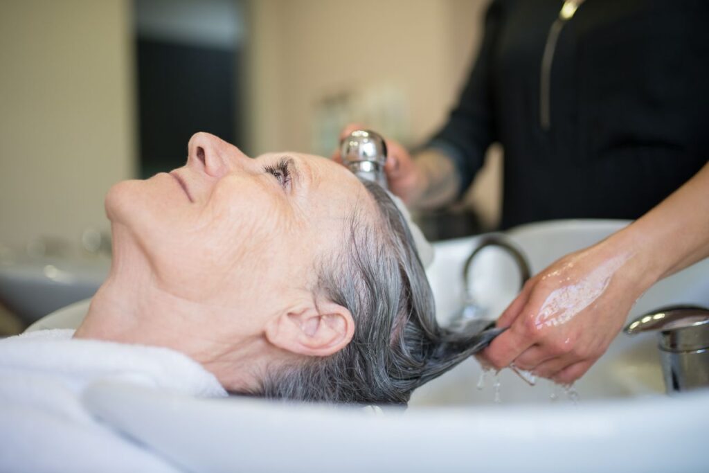 Elderly woman enjoying a relaxing hair wash session in a professional salon setting.