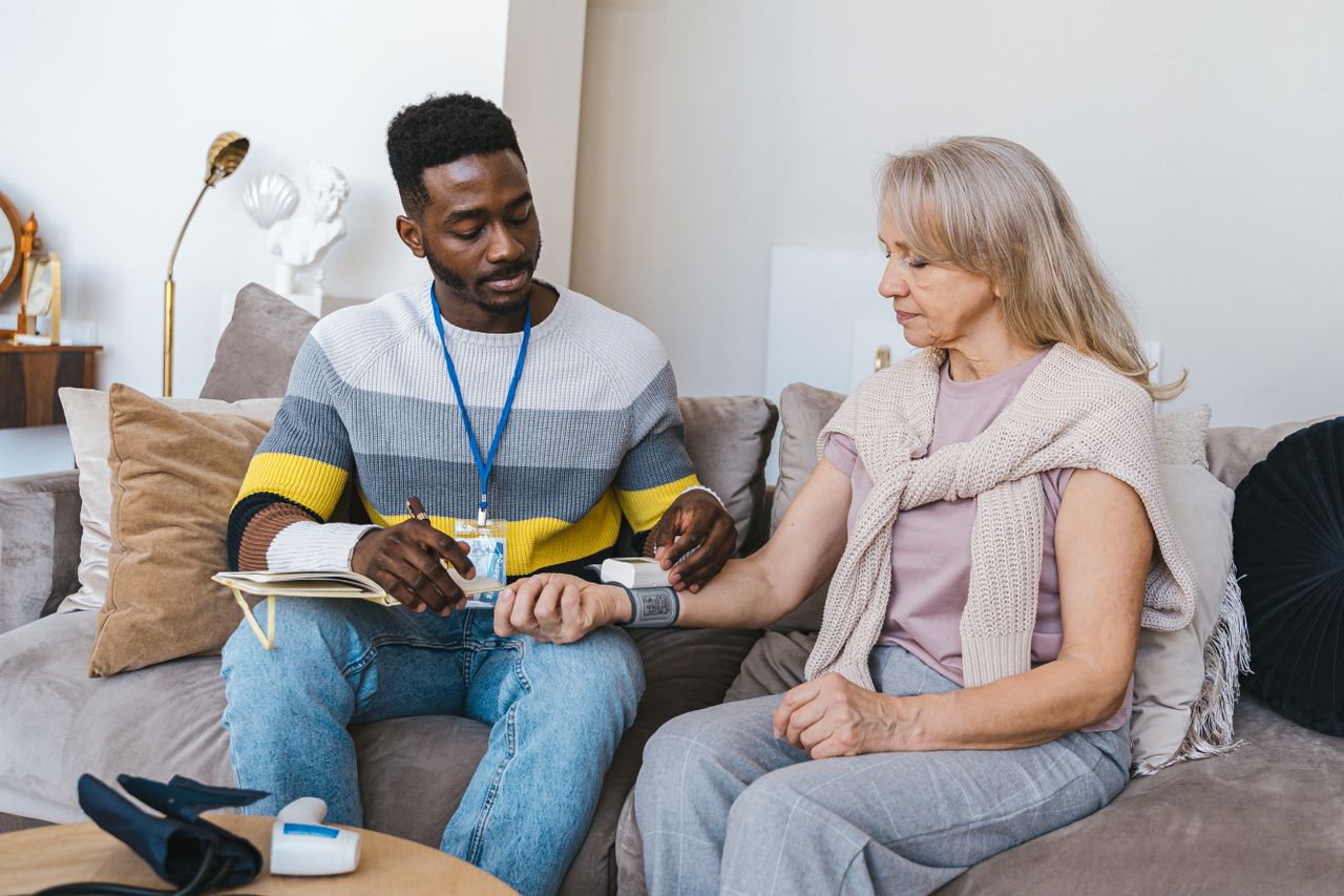 Mastering the First Impression: Your intriguing post title goes here Volunteer checking elderly womans blood pressure at home. Compassionate healthcare support.